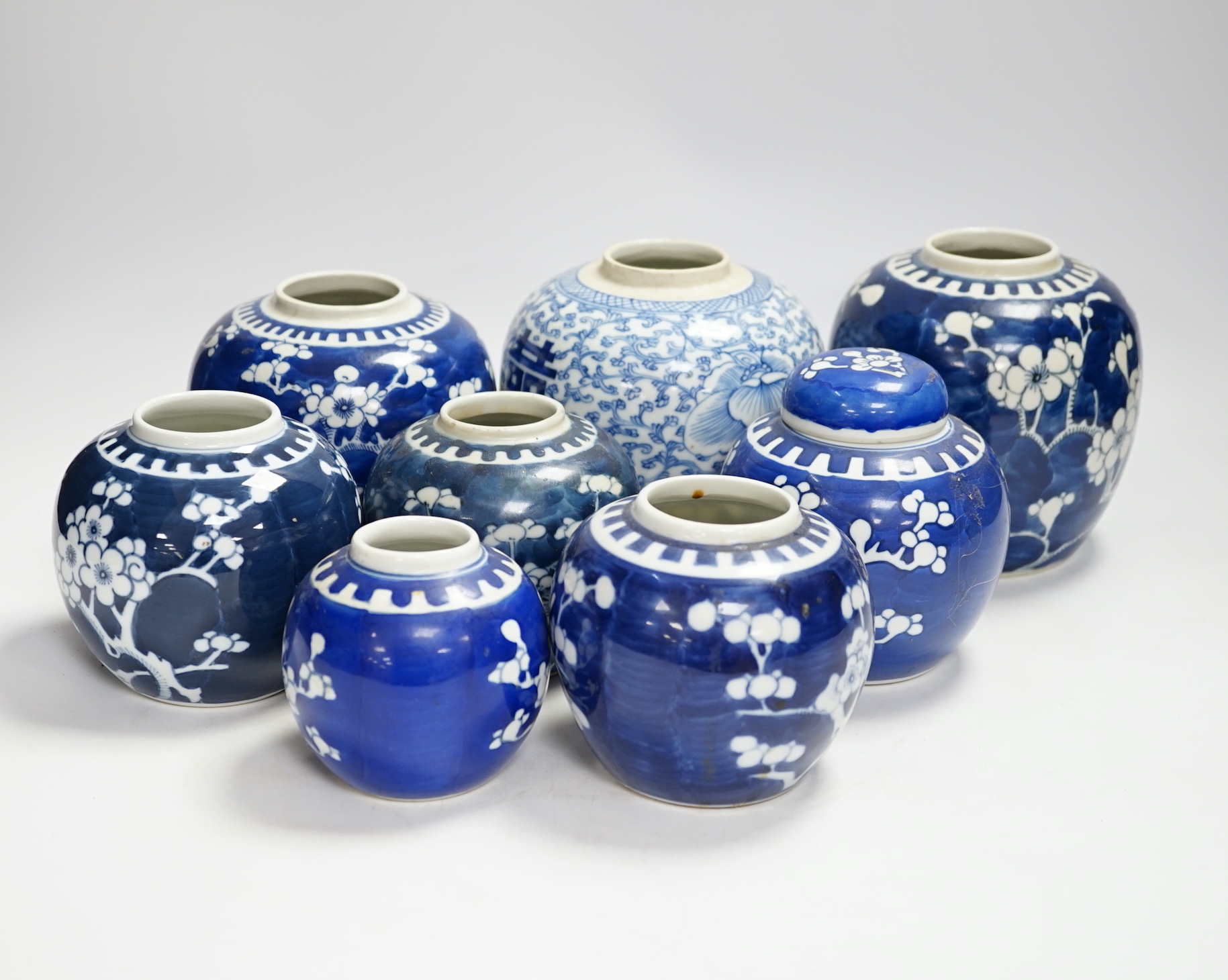 A Chinese blue and white 'shuangxi' jar, and seven blue and white 'prunus' jars and one cover, largest 14cm high (8)